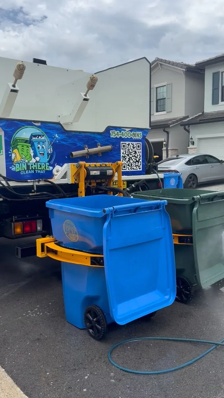 Blue bin locked into the cleaning truck's lift at the curb