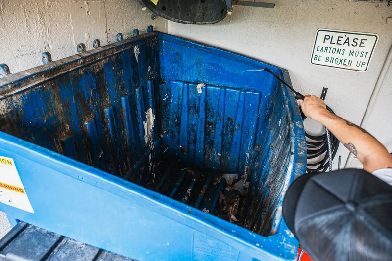Commercial dumpster before cleaning, walls coated in grime