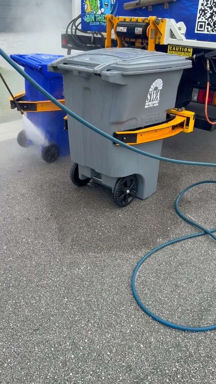Gray bin on the lift with steam rising during the wash