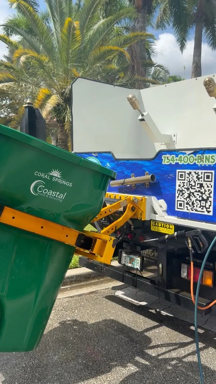 Green recycling bin tipped by the truck lift into the wash chamber